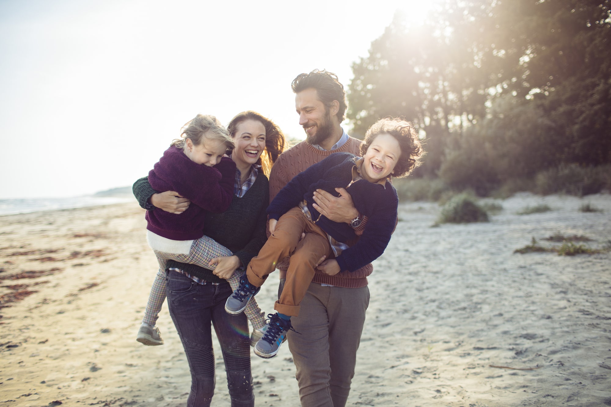 family of four walking on the beach smiling and laughing