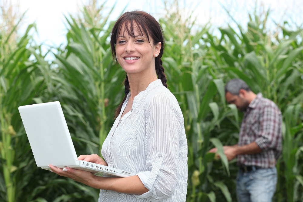 Showing two people in a farmers field evaluating crops